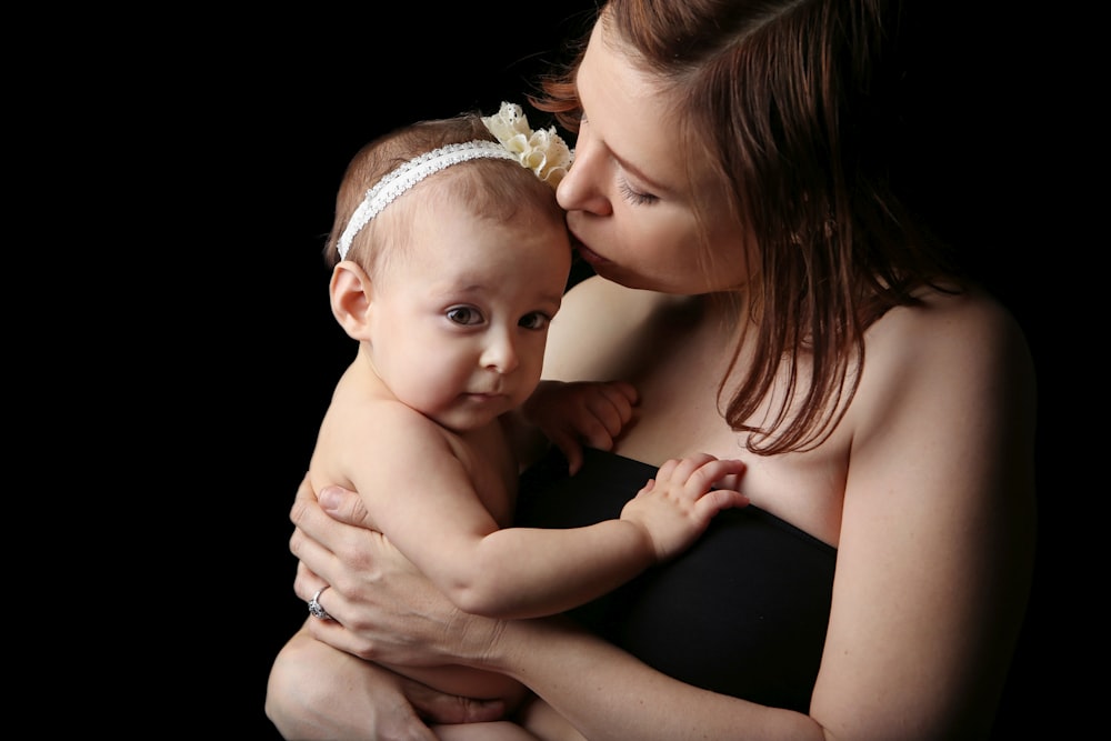 woman kissing baby inside dark room