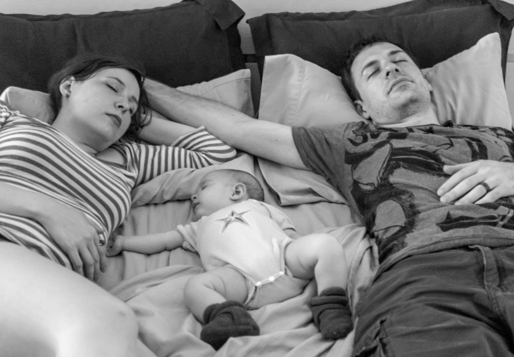 a man and a woman laying in bed with a baby