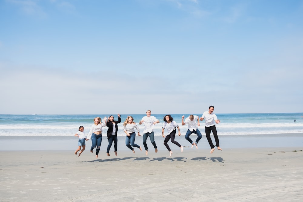 group of people jumping on seashore