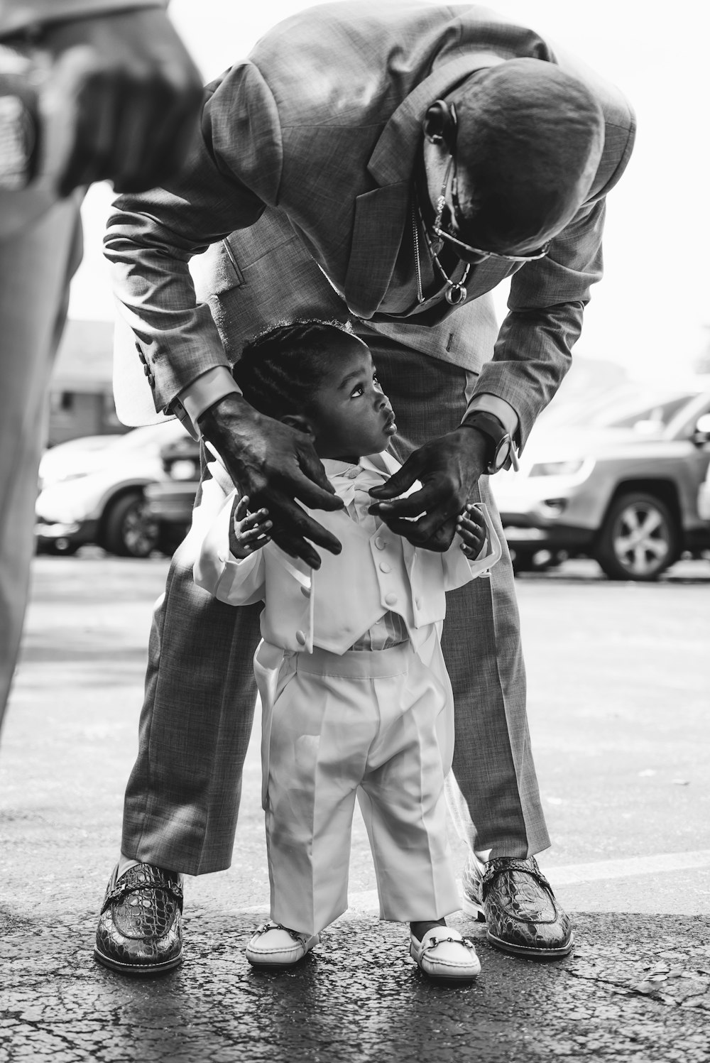 grayscale photo of man fixing boy suit