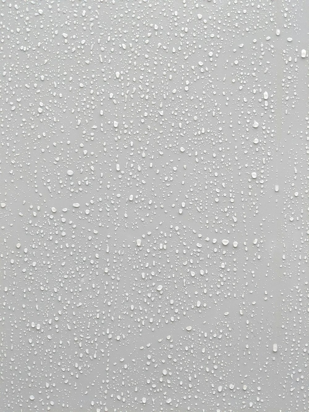Gotas de agua sobre una superficie de vidrio con un fondo blanco