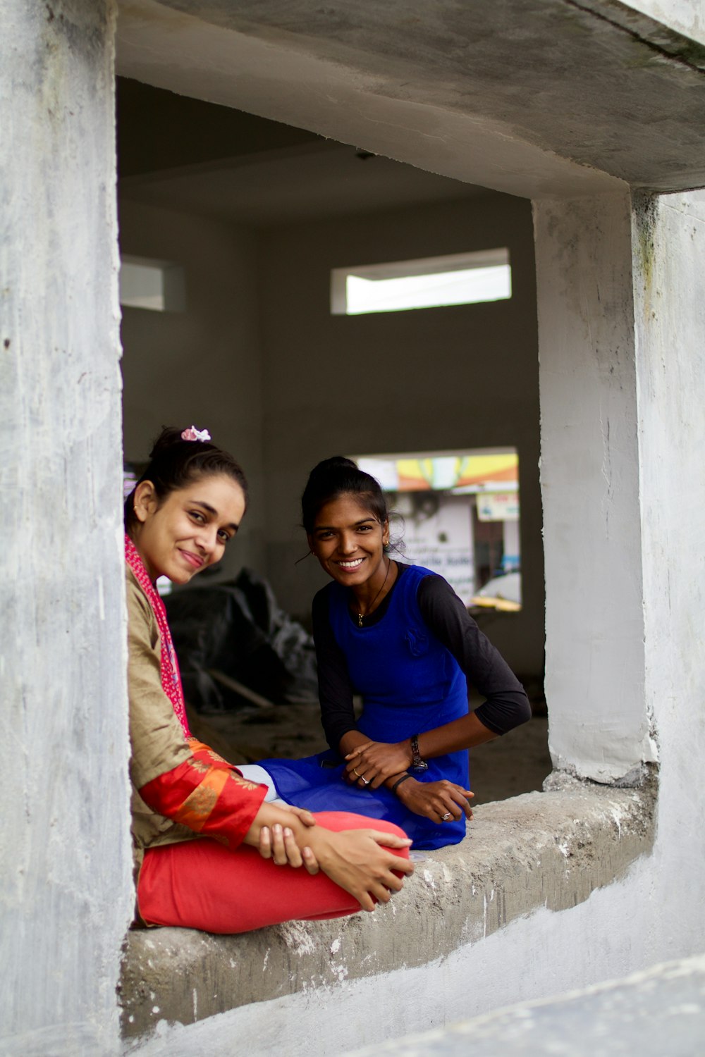 two smiling women sitting on window sill