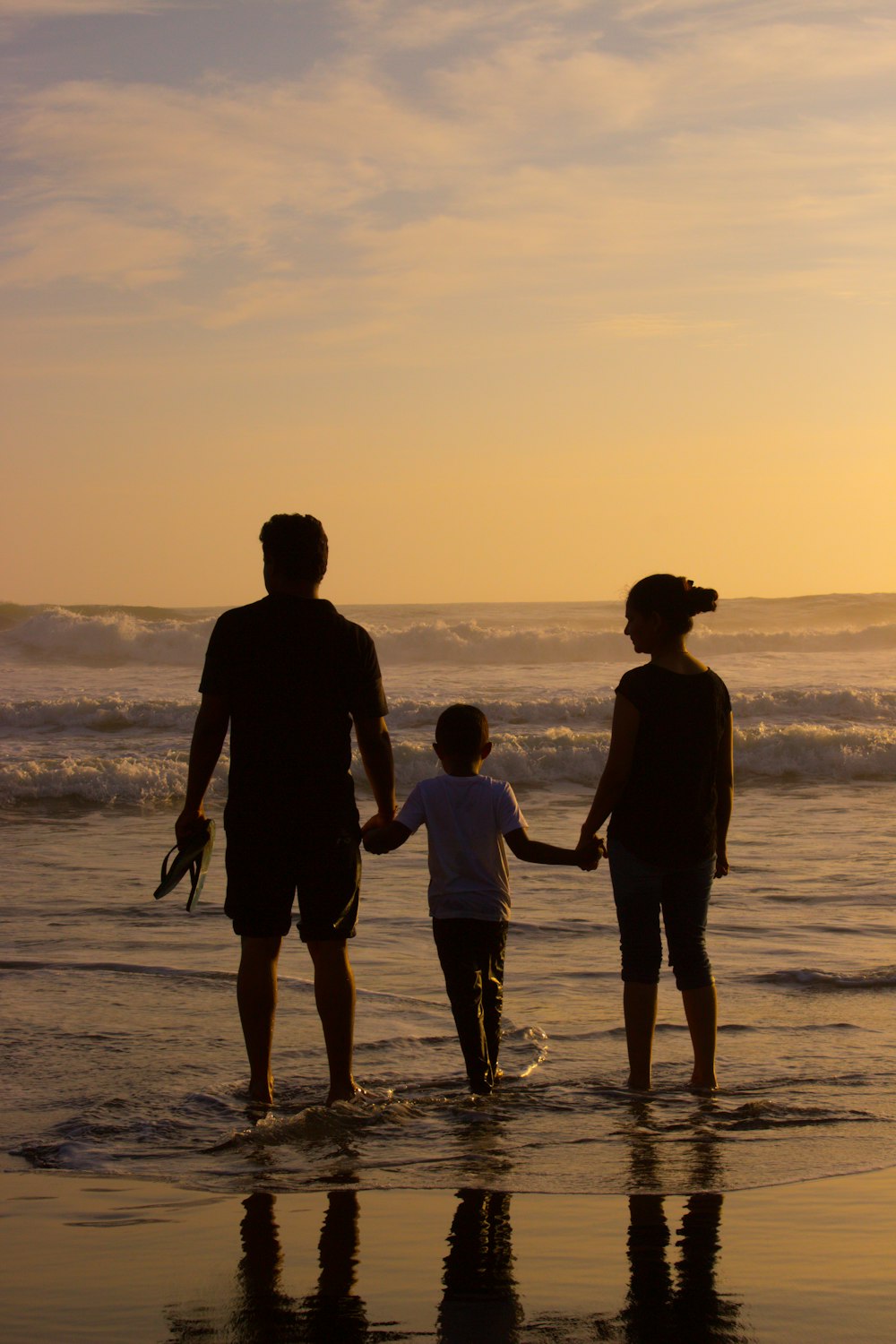 boy standing between woman and man