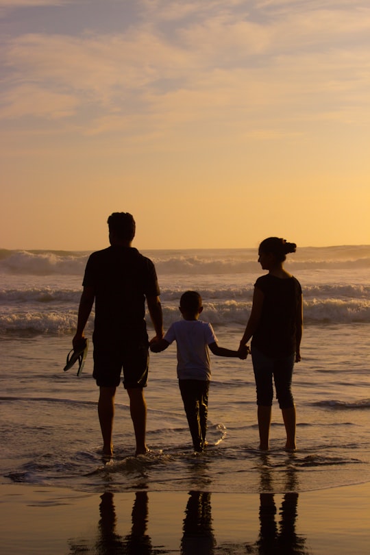 boy standing between woman and man in Kovalam India