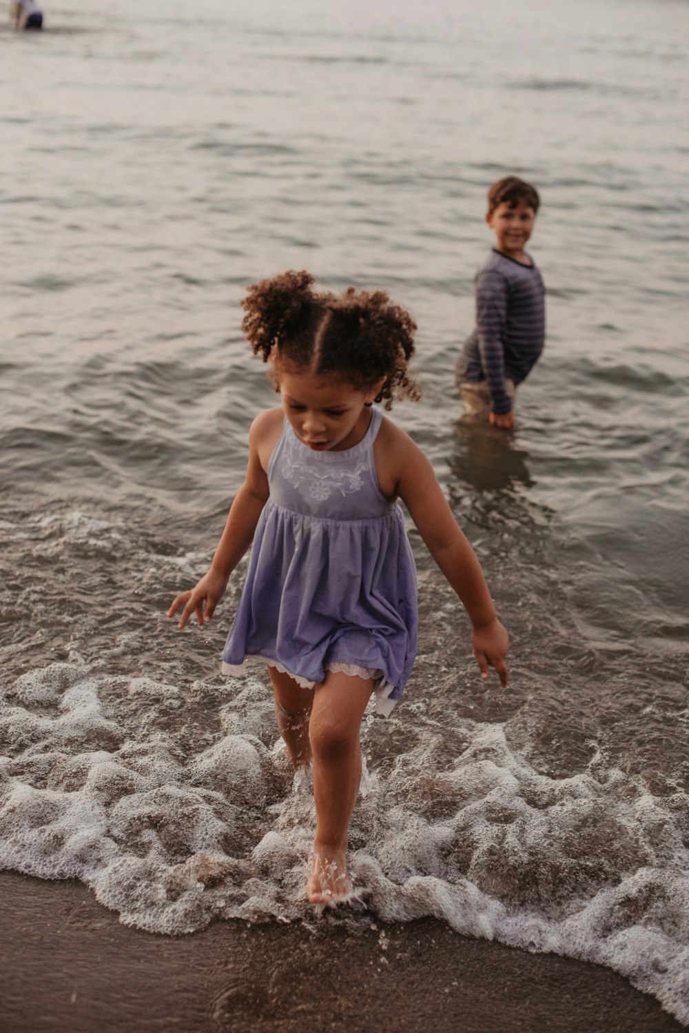 Mädchen trägt blaues ärmelloses Kleid am Meer