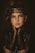 A young individual with a thoughtful expression is wearing a decorative headpiece and elegant clothing. The outfit includes lace and leather textures, creating a sophisticated and artistic style.