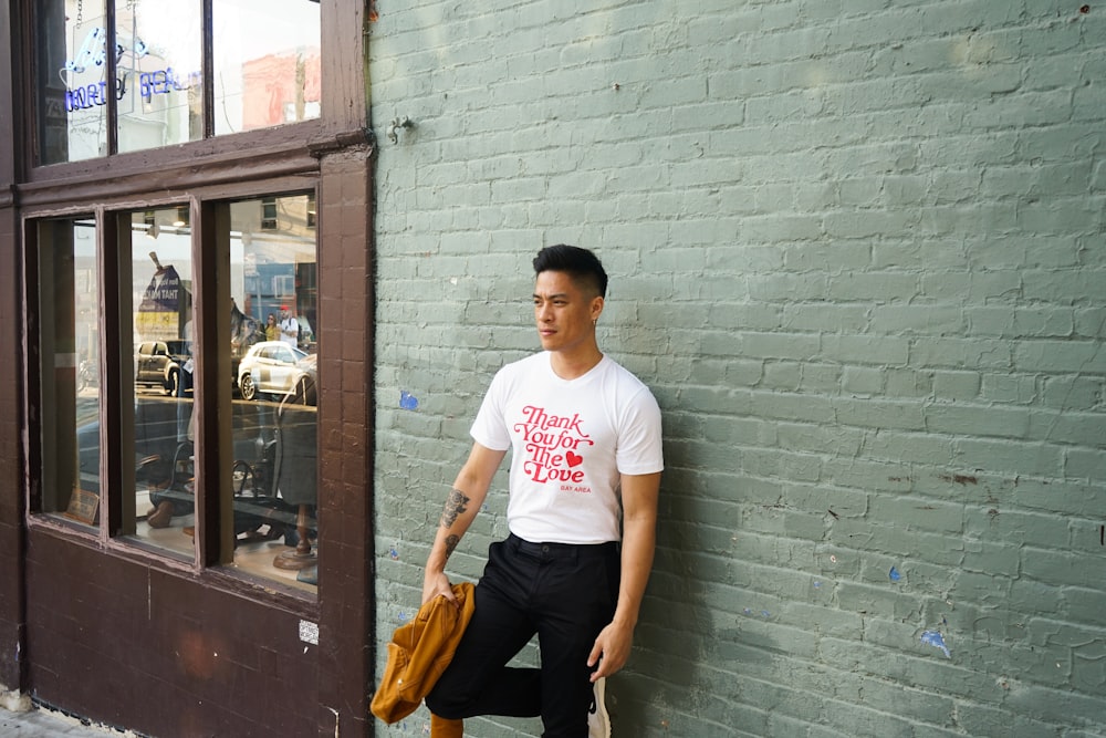 man leaning right foot on wall