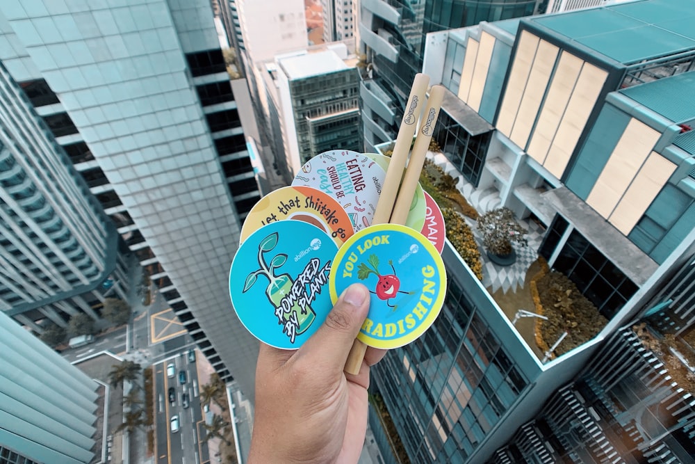 a person holding up two frisbees in front of a cityscape