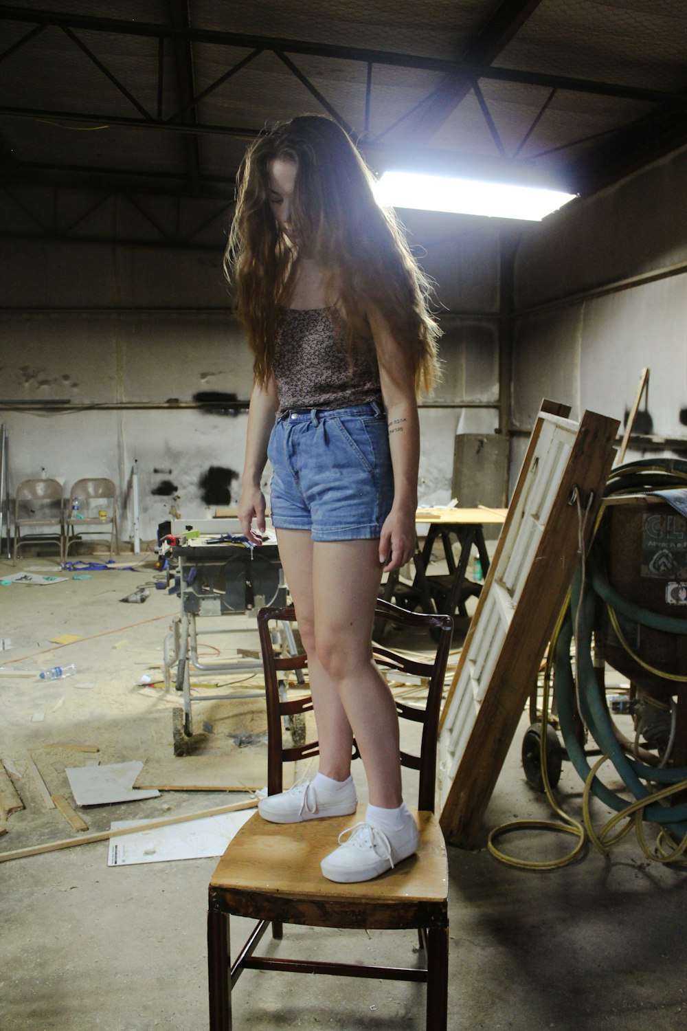 girl wearing blue shorts on brown wooden chair