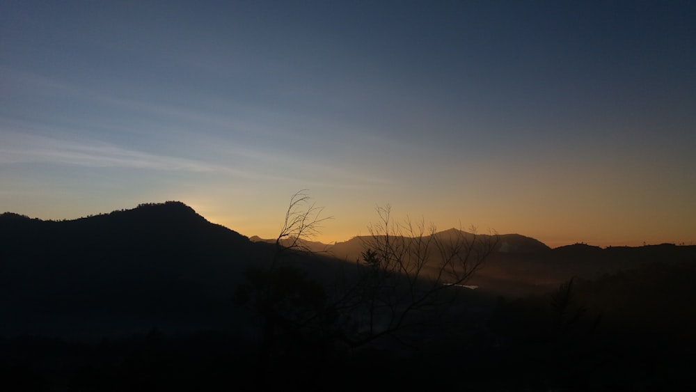 the sun is setting over a mountain range