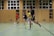 A group of diverse young players practicing indoor soccer in a well-lit gymnasium.