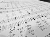 A close-up view of a sheet of music with musical notes and lyrics printed in black ink on a white background. The focus is on the lower part, where the notes and the words 'wake my spirit' and 'perish' are visible.