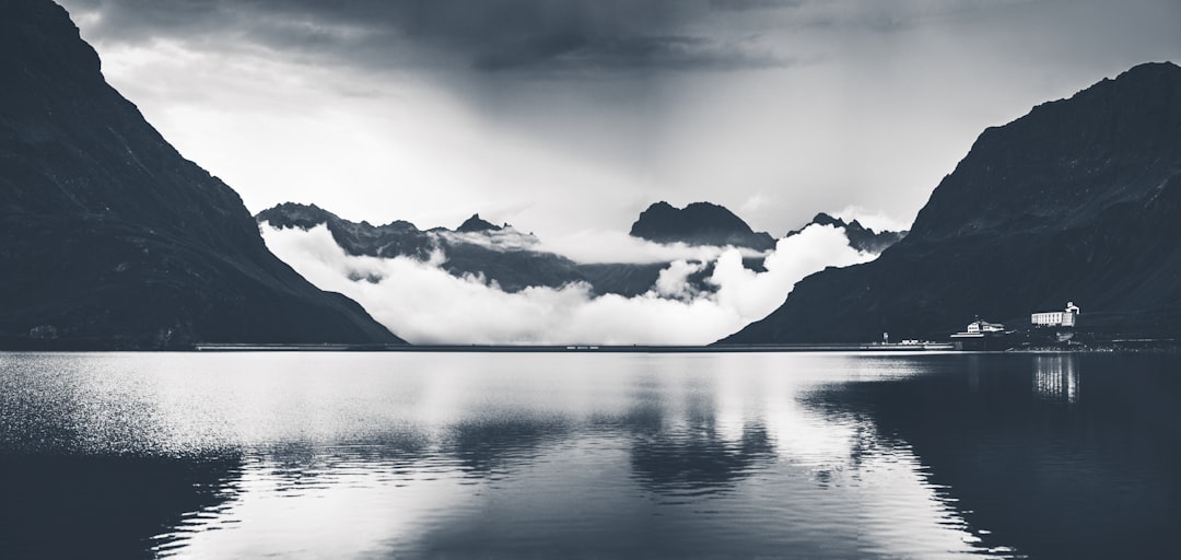 grayscale photo of body of water and mountains