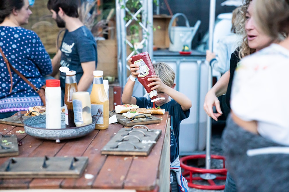 boy pouring sauce on bread at table