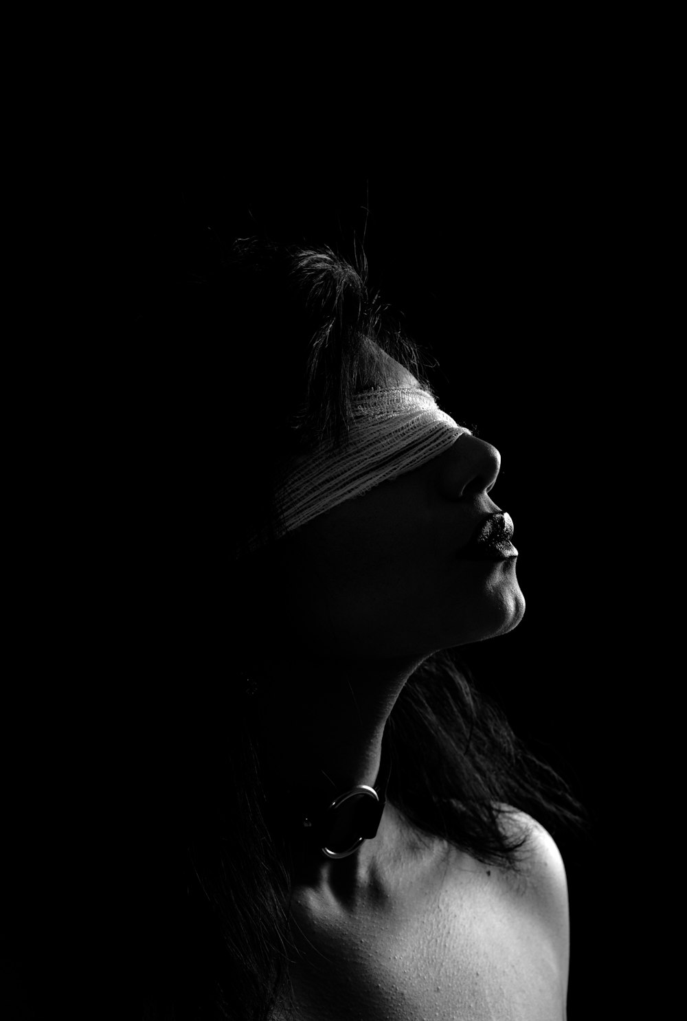 Photographie en niveaux de gris d’une femme portant un bandeau sur les yeux