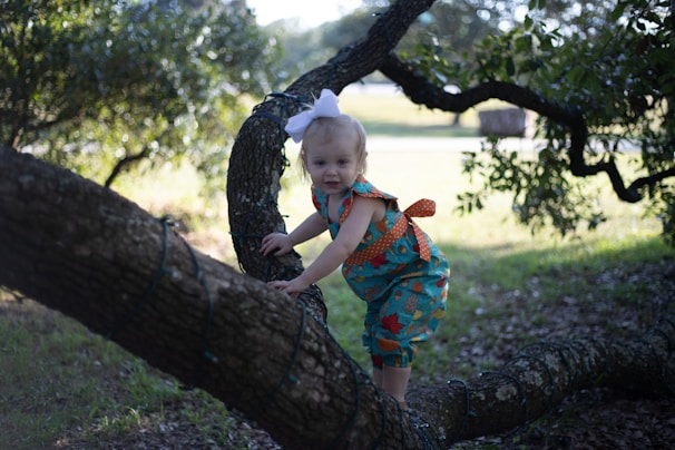 A little girl wearing a bright pink hair bow while playing in a park.
