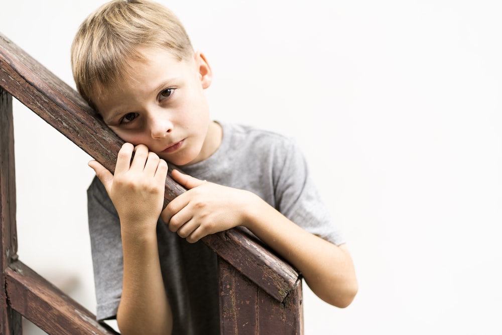 boy standing on stairs while holding hanrail