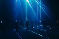 Team members collaborating around a holographic display in a dark room lit by purple and red lights.