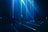 A group of people stand in a dark room with vibrant blue and green laser beams projecting vertically and horizontally around them. The atmosphere is immersive and futuristic, with shadows and light creating a dramatic effect.
