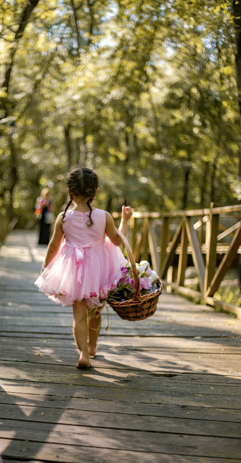 girl wearing pink tutu dress walking on brown wooden boardwalk