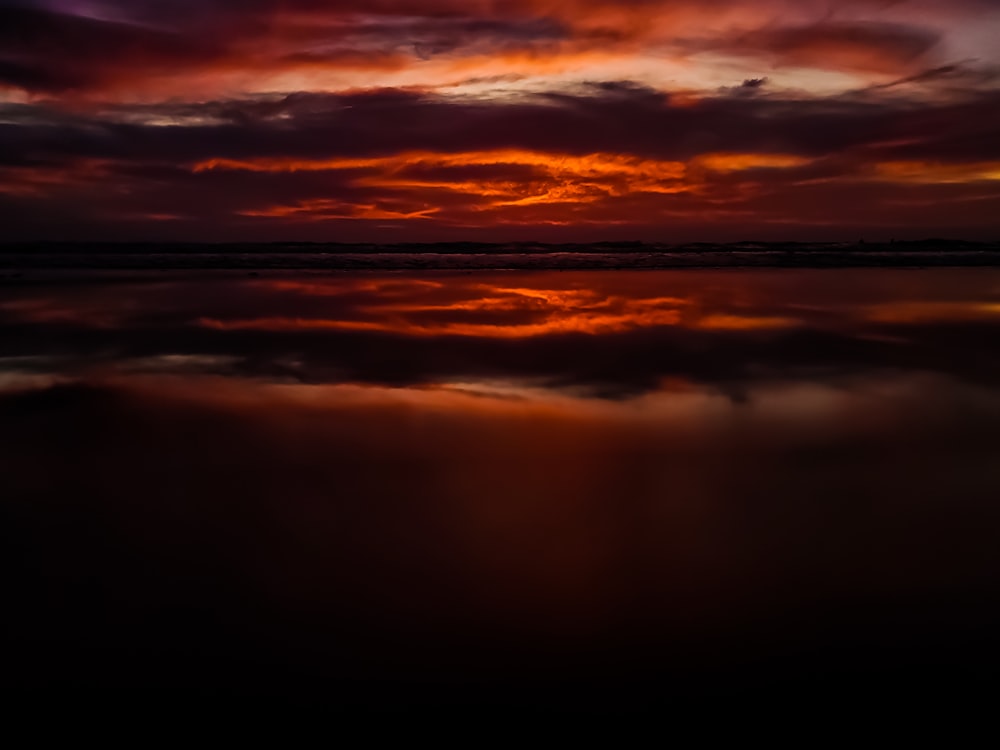 水域に沈む赤とオレンジの夕日