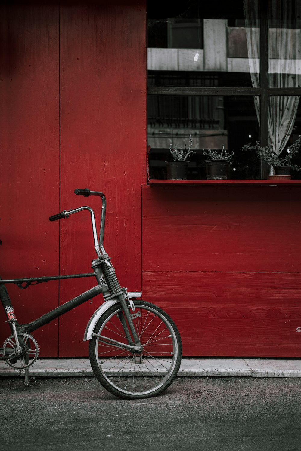 black and white bicycle parked beside red wall