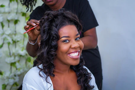Two Dominican sisters smiling warmly while styling a client's hair in a cozy salon setting.