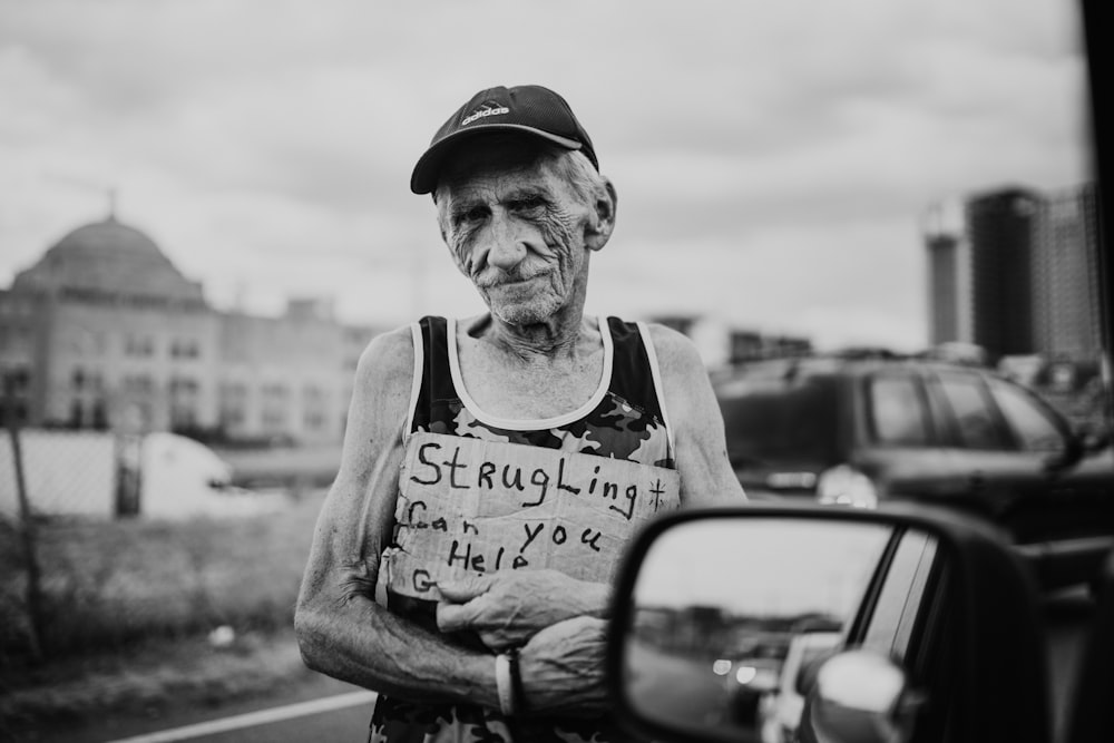 a man standing next to a car holding a sign