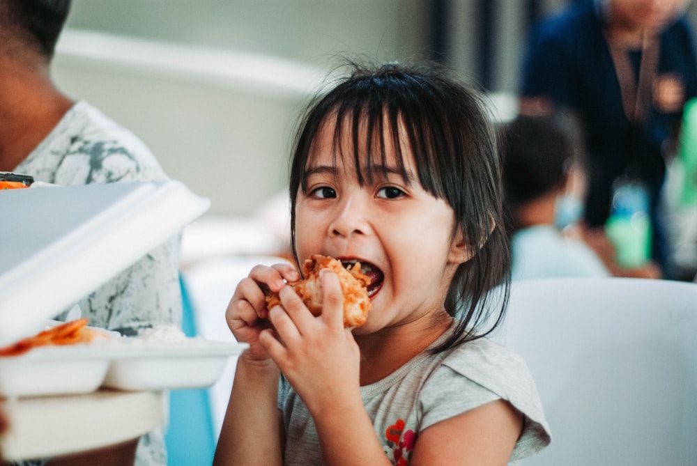 girl biting a good by table at daytime