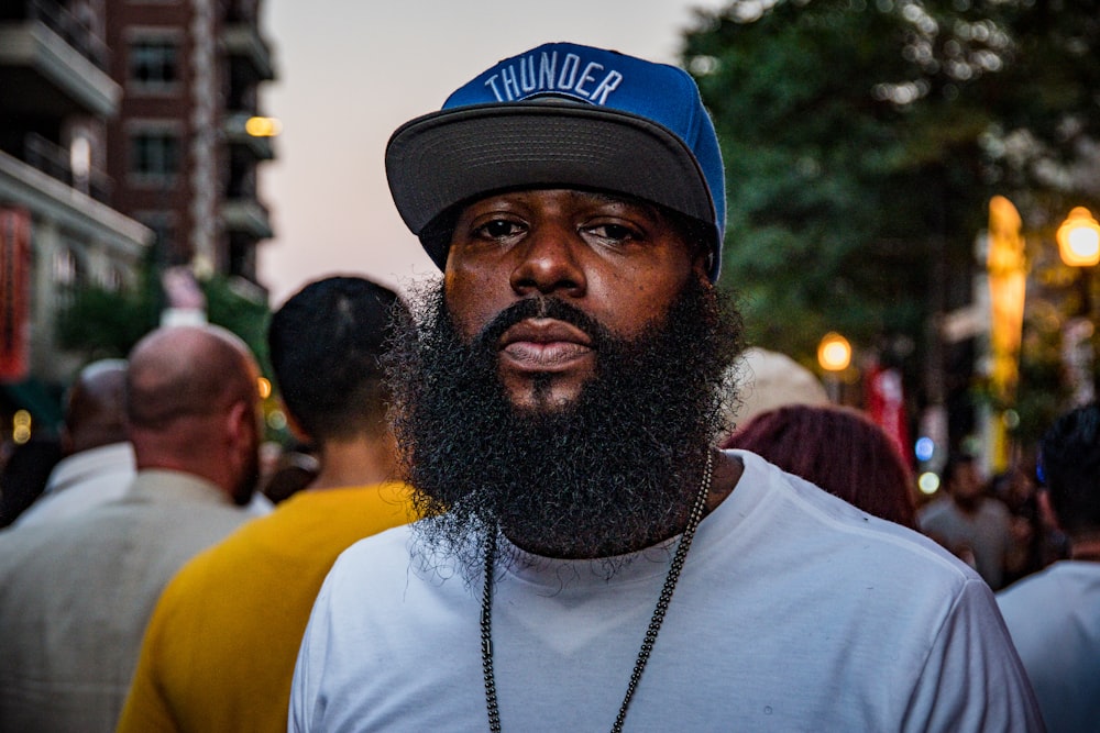 shallow focus photo of man in white crew-neck wearing blue flat brim cap