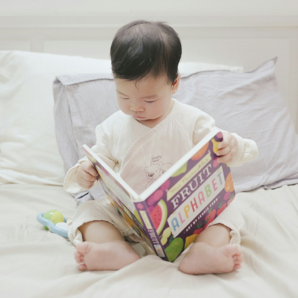 bébé tenant un livre de l’alphabet de fruits