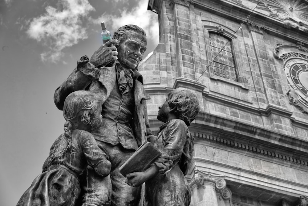 man holding bottle near two children statue