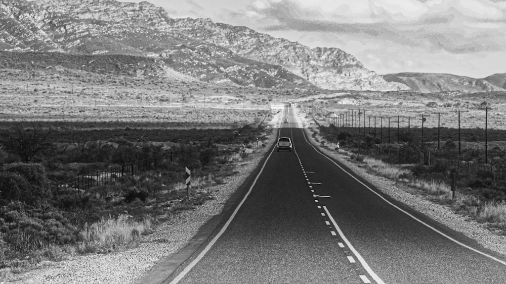 greyscale photo of highway between desesrt