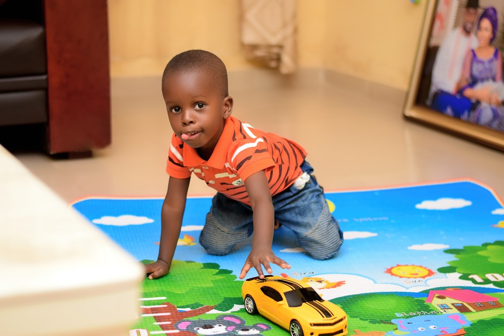 boy playing chevrolet camaro toy on floor