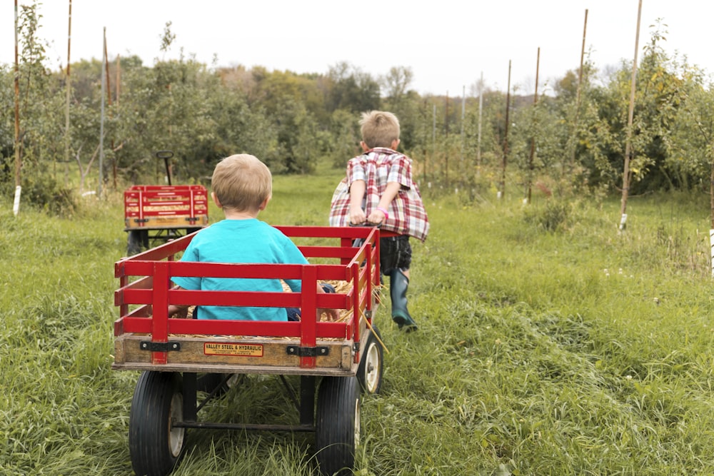 boy riding on a wagon being pulled by another boy