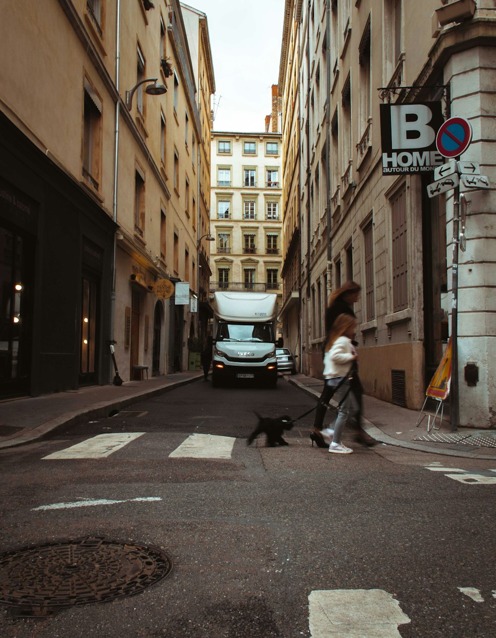 woman and dog crossing on road beside building