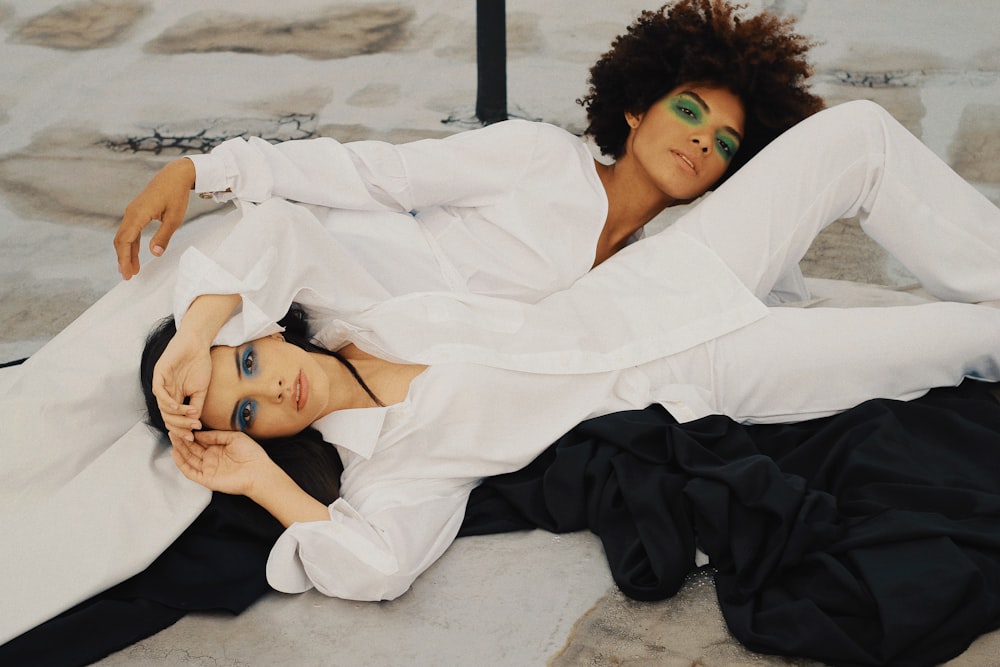 two women laying down wearing white dress shirts