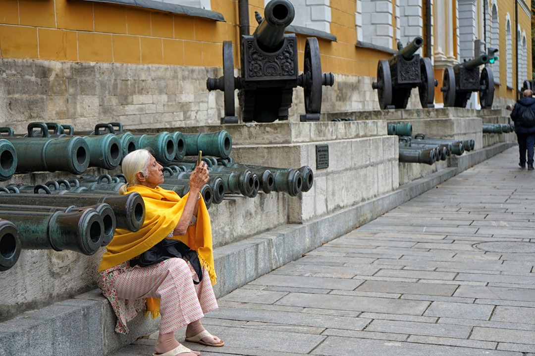 sitting woman beside canon taking photo using smartphone