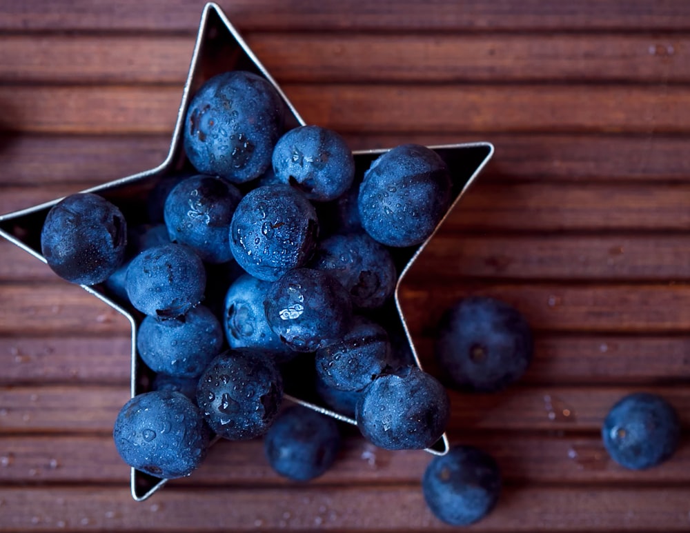 blueberries on wooden surface and in star-shaped bowl