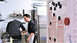 Hands holding a clipboard with food safety checklists in a professional kitchen.
