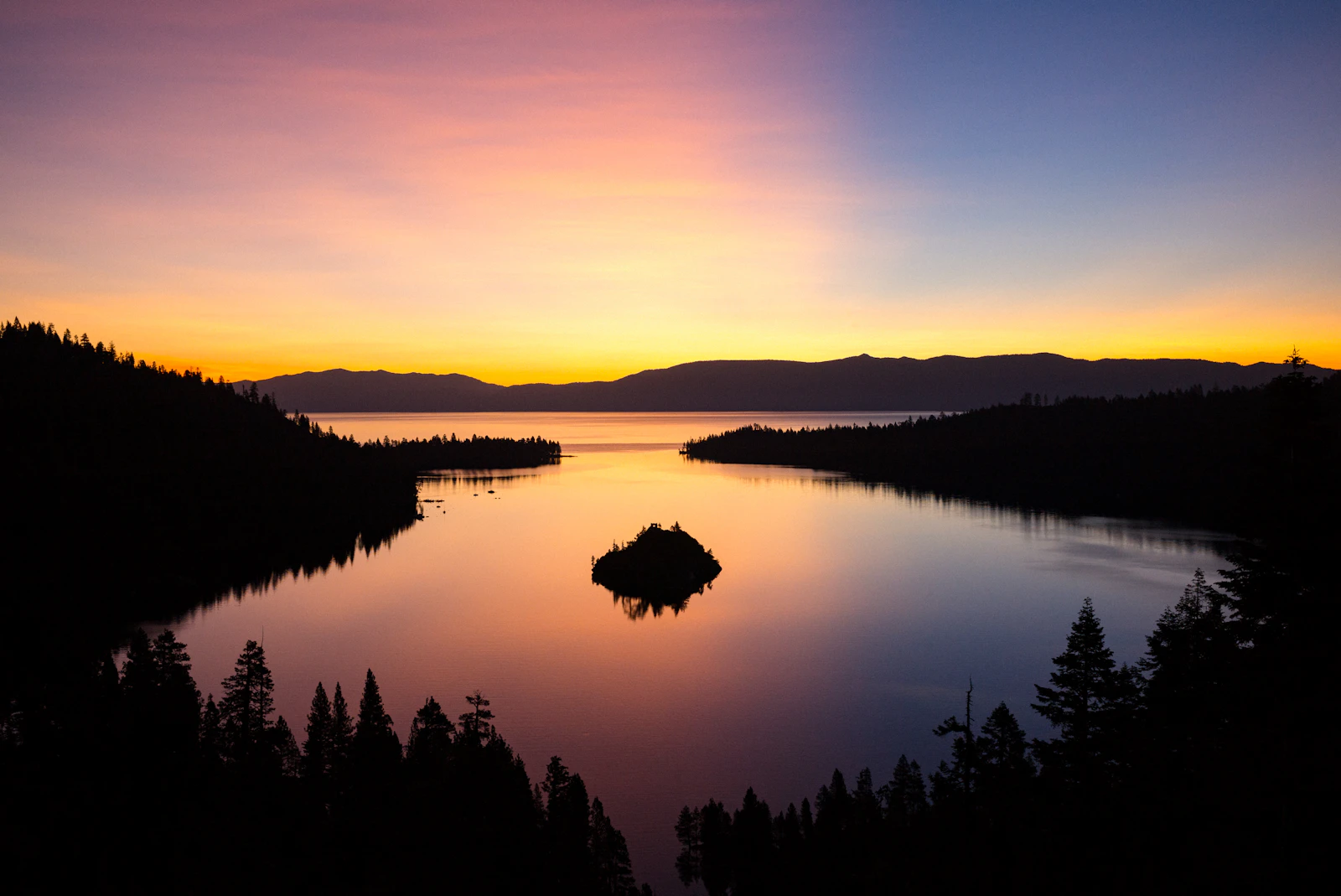 Lake Tahoe at sunrise, an island in the bay and the pines in silhouette