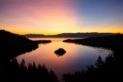Lake Tahoe at sunrise, an island in the bay and the pines in silhouette
