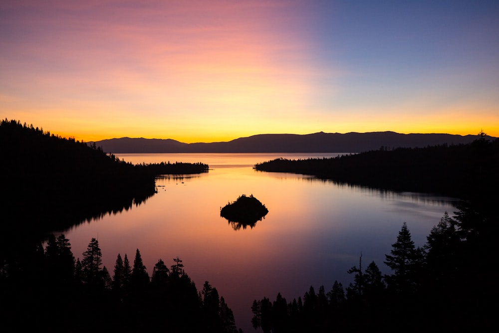 silhouette of trees and mountain near body of water