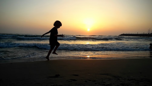 A joyful child and teenager practicing capoeira outdoors at sunset
