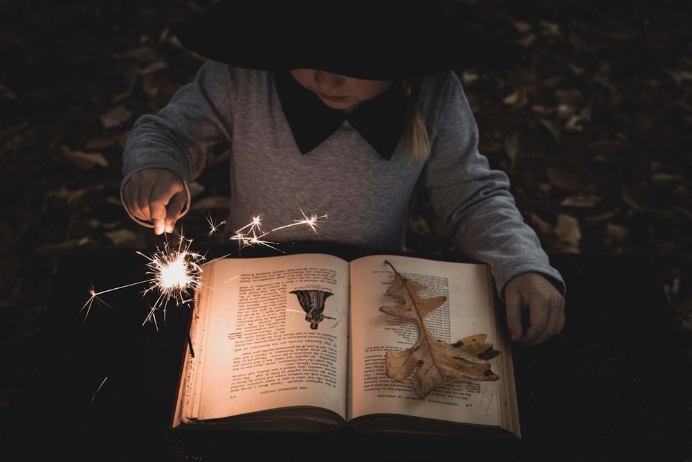 girl holding lighted sparkler while reading book