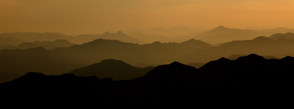 the sun is setting over a mountain range