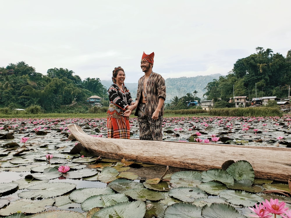 smiling man and woman beside boat