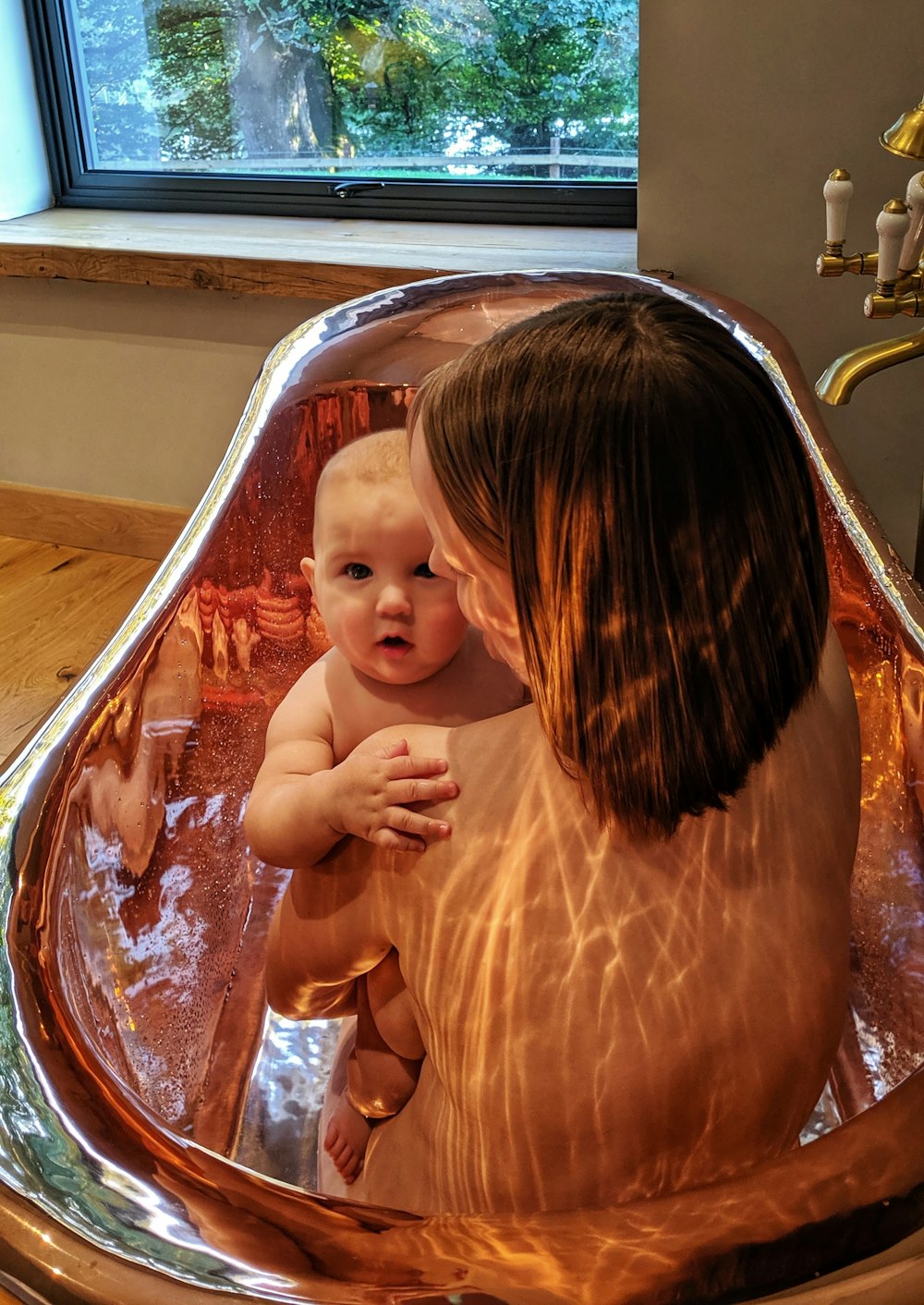 woman carrying baby sitting in bathtub close-up photography