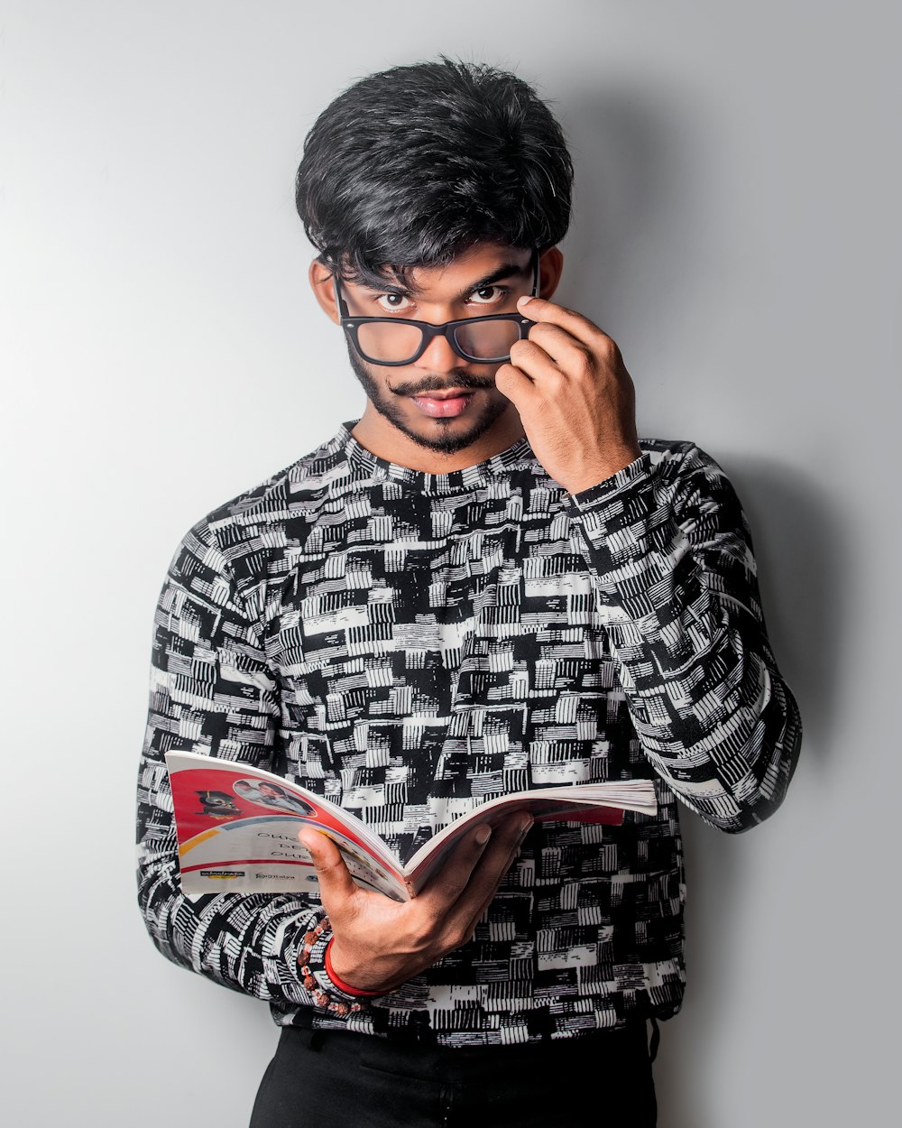 man wearing grey shirt and eyeglasses holding book
