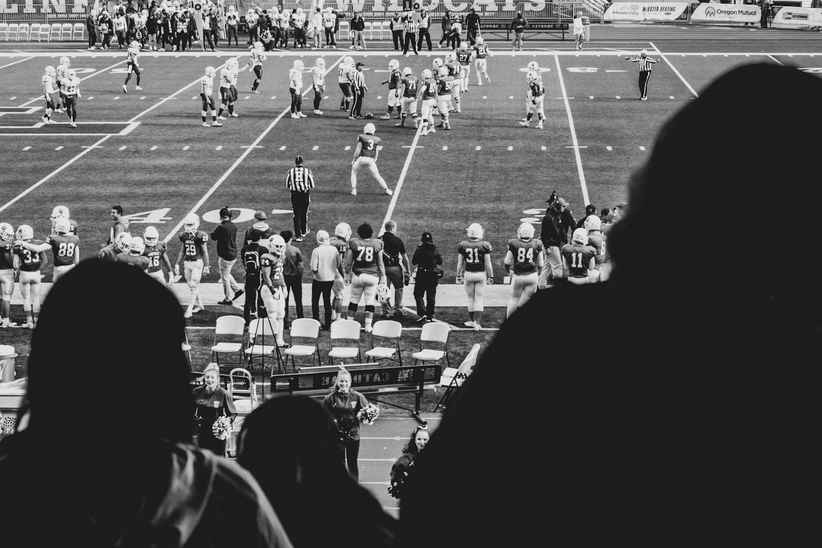 Black and white overhead view of a college football game with spectators around the field
